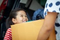 Happy asian child girl and mother helping to carry a cardboard box with stuffs moving into the car together to relocation Royalty Free Stock Photo