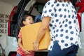 Happy asian child girl and mother helping to carry a cardboard box with stuffs moving into the car together to relocation Royalty Free Stock Photo