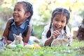 Happy asian child girls playing with little bunny rabbit with love and tenderness in the garden