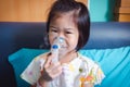 Happy asian child holds a mask vapor inhaler for treatment of asthma.