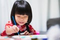 Happy Asian child painting water color on paper art. Sweet smile girl with lesson in class at homeschool. Kid wearing black apron Royalty Free Stock Photo