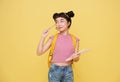 Happy Asian child student holding notebook and pencil with schoolbag isolated on yellow background. idea thinking and creative Royalty Free Stock Photo