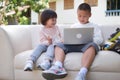 Happy Asian children schoolboy brother and little sister smiling sitting together on sofa using laptop computer at home, home Royalty Free Stock Photo