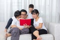 Happy Asian Chinese family reading book on the couch Royalty Free Stock Photo