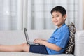 Happy Asian Chinese little boy using laptop on the sofa Royalty Free Stock Photo