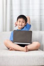 Happy Asian Chinese little boy using laptop on the sofa Royalty Free Stock Photo