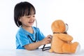 Happy Asian Chinese little doctor girl examine teddy bear