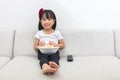 Happy Asian Chinese little girl eating popcorn on the sofa Royalty Free Stock Photo