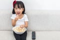 Happy Asian Chinese little girl eating popcorn on the sofa Royalty Free Stock Photo