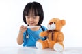 Happy Asian Chinese little girl examine teddy bear with thermometer Royalty Free Stock Photo