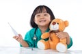 Happy Asian Chinese little girl examine teddy bear with thermometer Royalty Free Stock Photo