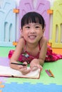 Happy Asian Chinese little girl laying on the floor coloring Royalty Free Stock Photo