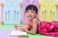 Happy Asian Chinese little girl laying on the floor coloring Royalty Free Stock Photo