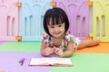 Happy Asian Chinese little girl laying on the floor coloring Royalty Free Stock Photo