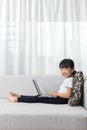 Happy Asian Chinese little girl lying on sofa with laptop Royalty Free Stock Photo