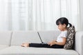 Happy Asian Chinese little girl lying on sofa with laptop Royalty Free Stock Photo