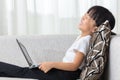 Happy Asian Chinese little girl lying on sofa with laptop Royalty Free Stock Photo