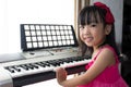 Happy Asian Chinese little girl playing electric piano keyboard Royalty Free Stock Photo