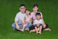 Happy Asian Chinese parents and daughters sitting on the grass