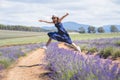 Trendy young girl wearing sunglasses and white hat jump over row of lavender flowers