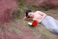 Happy Asian Chinese woman girl lying on grass dream pray flower field autumn fall park lawn hope nature read book knowledge Royalty Free Stock Photo