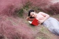 Happy Asian Chinese woman girl lying on grass dream pray flower field autumn fall park lawn hope nature read book knowledge Royalty Free Stock Photo