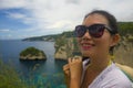 Happy Asian Chinese woman in sunglasses enjoying amazing coast scene from view point at tropical paradise beach with diamond rock Royalty Free Stock Photo