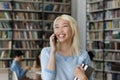 Happy Asian college student talking on cellphone in college library Royalty Free Stock Photo