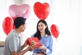 Happy Asian couple celebrating anniversary their love together, boyfriend giving red present gift box to surprised girlfriend, Royalty Free Stock Photo