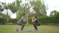 Happy asian couple doing exercises on grass in the park at the day time. People having fun outdoors. Royalty Free Stock Photo