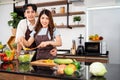 Happy Asian couple looking at the camera, cooks a healthy salad with vegetables together in the home kitchen. Food cooking. Royalty Free Stock Photo