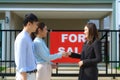 Happy Asian couple looking for their new house and shake hands with real estate broker after a deal. Young couple handshaking real Royalty Free Stock Photo