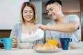 happy asian couple in pajamas sitting at table in kitchen at home in morning and having cereal breakfast together.husband pour mi Royalty Free Stock Photo