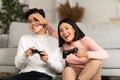 Happy Asian Couple Playing Computer Video Game Sitting At Home Royalty Free Stock Photo