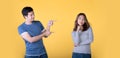 Happy Asian couple pointing fingers at empty copy space for text over yellow background Royalty Free Stock Photo