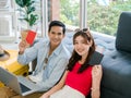 Happy Asian couple ready to trip, young man and woman, holding and showing passport while using laptop computer. Royalty Free Stock Photo