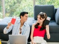 Happy Asian couple ready to trip, young man and woman, holding and showing passport while using laptop computer. Royalty Free Stock Photo