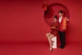 Happy asian couple in red casual attire holding angpao or red packet monetary gift and gold ingot bless with text means great luck