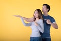 Happy Asian couple showing empty copy space on the open hands palm for text and pointing with fingers over yellow background Royalty Free Stock Photo