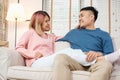 Happy asian couple sitting on sofa after unpacking cardboard boxes  while moving to new home at sofa in living room.new house Royalty Free Stock Photo