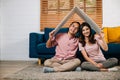 Happy Asian couple in their new apartment assembles cardboard home roof Royalty Free Stock Photo