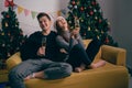 Happy Asian couple toasting champagne together, sitting on the sofa in the evening with a Christmas tree. Royalty Free Stock Photo