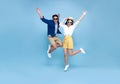 Happy Asian couple tourist jumping celebrating to travel on summer holiday isolated on blue background Royalty Free Stock Photo