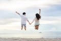 Happy Asian couple tourists jumping on beach vacations. Travel concept of young couple cheering for summer holidays showing Royalty Free Stock Photo