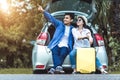 Happy Asian couple traveling and sitting in a car open trunk and watch sunrise. Royalty Free Stock Photo