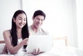 Happy Asian couple using laptop on morning bed with smile Royalty Free Stock Photo