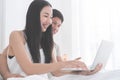 Happy Asian couple using laptop on morning bed with smile Royalty Free Stock Photo