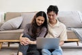 Happy asian couple using laptop sit relax on floor doing ecommerce shopping online on website at home Royalty Free Stock Photo
