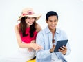 Happy Asian couple, young woman with beach hat and man in denim shirt sit on suitcase. Royalty Free Stock Photo