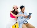 Happy Asian couple, young woman with beach hat and man in denim shirt sit on suitcase. Royalty Free Stock Photo